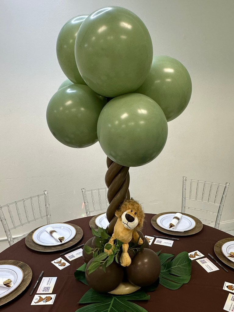 Lion themed balloon centerpiece displayed on a guest table during Prince Elijah's baby shower.