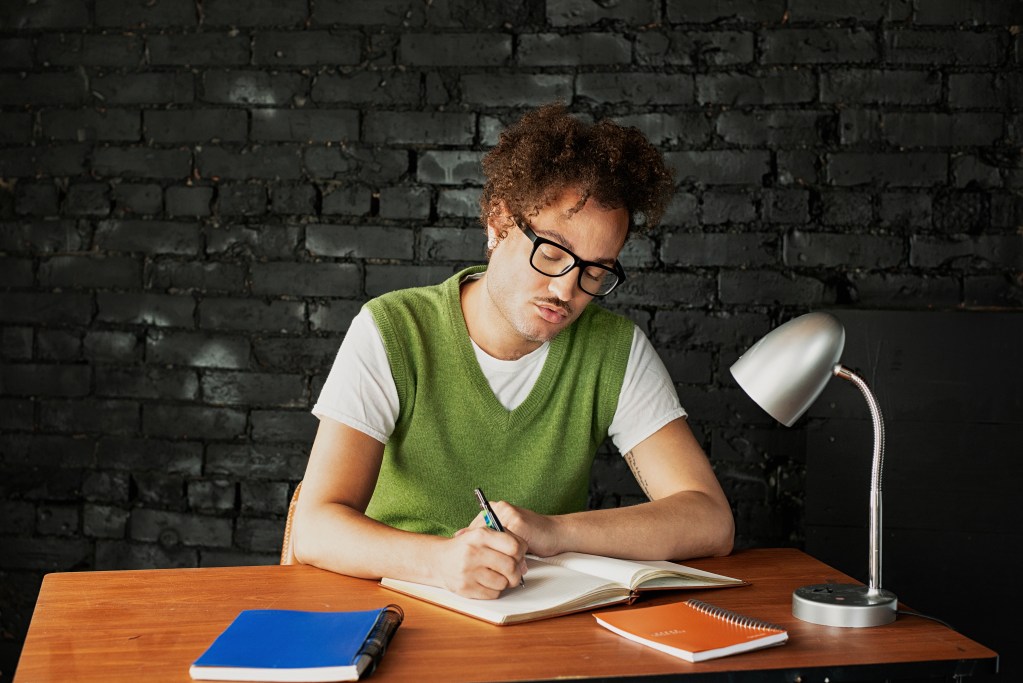 Kevie The Dreamer writing in a notebook while reflecting on his travel experiences for his personal blog.